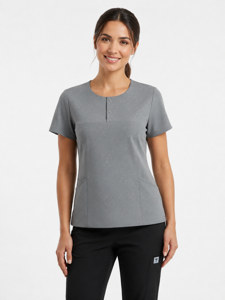Modelo muestra Uniforme clínico gris vista frontal con dos broches, bolsillos y corte cómodo